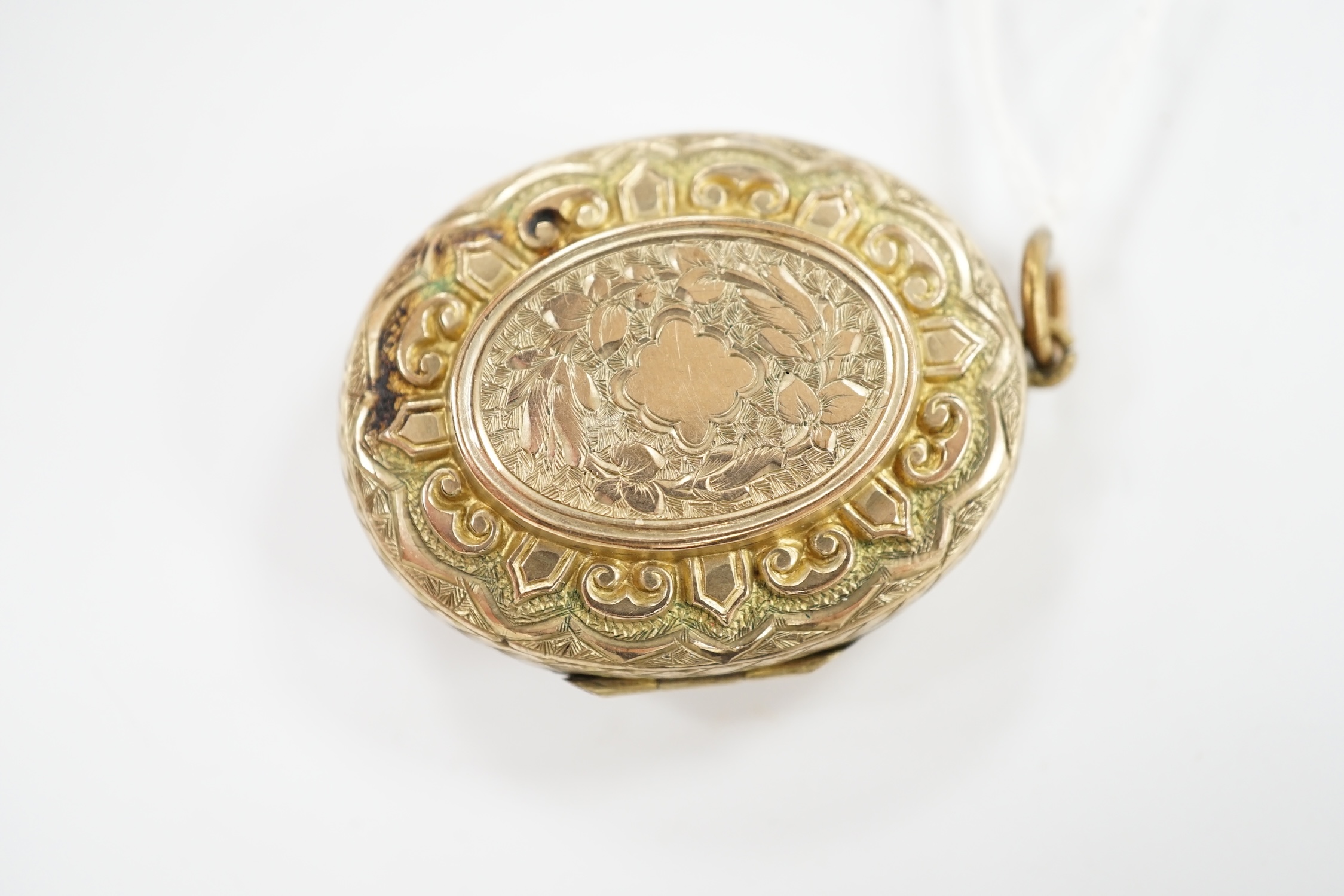 A Victorian engraved yellow metal overlaid, garnet and seed pearl set oval locket, 37mm. Condition - fair